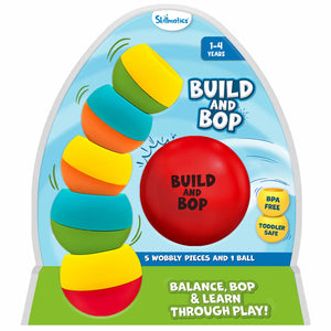 This image shows the Skillmatics Build and Bop toddler toy packaging, featuring five brightly coloured wobbly pieces stacked in a tilted tower on the left and a large red soft ball labeled “Build and Bop” in the centre. The packaging highlights “1–4 years,” “BPA free,” “toddler safe,” and a green base that reads “Balance, bop & learn through play!” with a blue sky-style background.