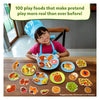 Young girl in chef’s hat and apron with realistic play food on toy plates