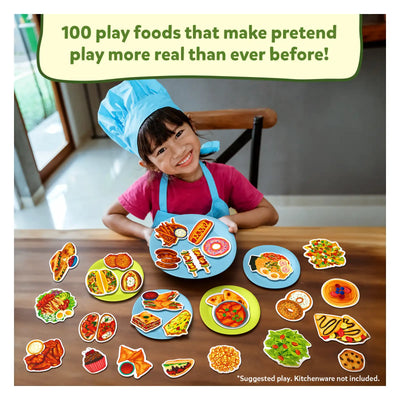 Young girl in chef’s hat and apron with realistic play food on toy plates