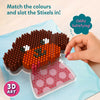 Close-up instructional view of Skillmatics Stixels 3D art activity showing a hand placing a pink stixel peg into a transparent base board to form a puppy face design. The image emphasizes color matching, slot-and-fill technique, with cylindrical pegs creating a textured mosaic effect.
