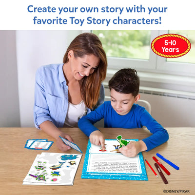 A smiling woman in a blue shirt and a boy in a blue top sit at a wooden table using the Skillmatics Toy Story My Story Art Kit. The boy places character stickers onto a blue story pad while the woman holds a vocabulary card. Markers, sticker sheets, and written story pages are spread on the table. Age label reads "5–10 Years."