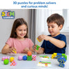 Two young children sit at a table smiling while stacking patterned geometric blocks and spheres from the Brain Blocks set. The image shows cubes, triangles, hourglass shapes, and balls arranged into small structures, with challenge cards nearby. A STEM Learning badge and the text “3D puzzles for problem solvers and curious minds” appear above the play scene.