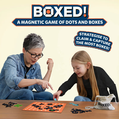 A smiling family of three — a woman, a man, and a young girl — playing Skillmatics Boxed! on a wooden table. They are engaged in the magnetic dots and boxes game, strategizing their moves with magnetic pieces and dots. The game board is visible in the center with colourful pieces placed on it. The text “The perfect game for thinkers, strategists, and nostalgists!” appears at the top with the tagline 