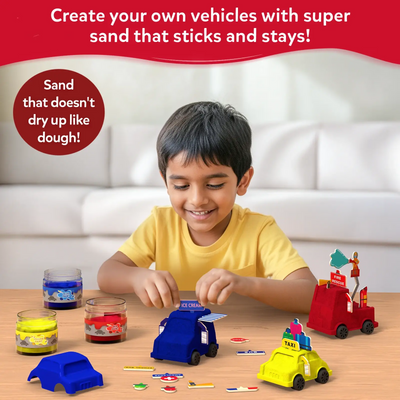 A young boy sits at a table shaping blue kinetic sand into a vehicle using the moulds from the Sandeezy kit. Three jars of sand in blue, red, and yellow are placed beside him along with signs and accessories for decorating vehicles like taxi, ice-cream, and fire rescue. Text above reads “Create your own vehicles with super sand that sticks and stays,” with a circular badge saying the sand doesn’t dry like dough.