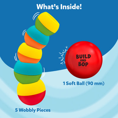 This image displays the Build And Bop toy contents against a blue background. Five multicoloured, wobbly pieces are shown stacked with motion lines indicating wobble, and a red soft ball labeled “Build And Bop” is placed to the right. The text reads “What’s Inside!” above, and lists “5 wobbly pieces” and “1 soft ball (90 mm)” beneath the illustrations.