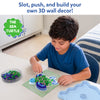 Young child seated at a table creating a 3D sea turtle artwork with the Skillmatics Stixels kit. The child places colorful Stixels into a transparent turtle-shaped base using the color guide, while loose Stixels and the decorative display frame are arranged nearby in a bright indoor setting.