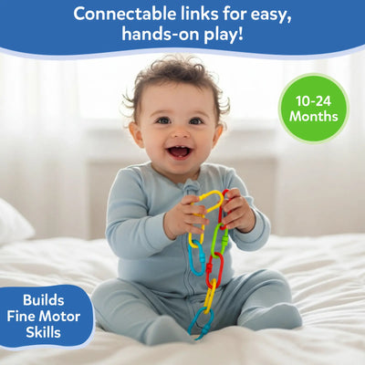 Smiling baby seated on a white bed holding several colorful Skillmatics Linkies connected together, demonstrating real-life use. The baby wears a light blue onesie and grips the links with both hands. Text on the image states “Perfectly sized for tiny fingers,” with an age indicator of 10–24 months and a callout noting fine motor skill development.
