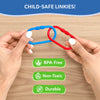 Close-up of adult hands holding two interlocked plastic links in blue and red over a wooden surface, demonstrating connection strength. Text reads “Child-safe Linkies,” with icons and labels below indicating BPA-free, non-toxic materials, and durable construction. The image focuses on safety, material quality, and secure linking design without showing a child.