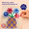 Close-up of the Skillmatics Stixels Flower Vase project showing colorful Stixels inserted into a transparent base to create flowers and a patterned vase. A hand places a red Stixel into an open slot while matching colors to the guide, highlighting the tactile 3D art-building activity.
