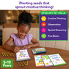 A young child sits at a wooden table using the Skillmatics Picture Sprouts activity book and coloring a drawing with retractable crayons. Additional completed pages and the crayon box are placed nearby. A side panel lists creative thinking, observation, spatial reasoning, and fine motor as key skills.