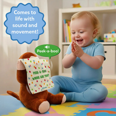 A seated toddler in a light blue romper claps with excitement while watching a brown plush monkey lift a polka-dotted cloth printed with “Peek-a-boo, where are you?” A green speech bubble shows the phrase “Peek-a-boo!” and curved motion lines indicate the monkey’s arms moving. A blue starburst graphic above states “Comes to life with sound and movement!” The scene is set on a soft play mat indoors.