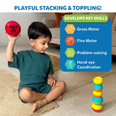 A toddler sits cross-legged on a rug indoors, holding a red Build And Bop ball above their shoulder while looking toward a colourful stack of wobbly pieces arranged in a tower on the floor. At the top, text reads “Playful Stacking & Toppling!” On the right, a blue panel titled “Develops Key Skills” lists icons for 'gross motor', 'fine motor', 'problem-solving', and 'hand-eye coordination' in bright, toddler-friendly colours.