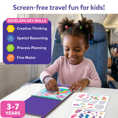 miling girl with colorful hair ties in a pink sweater using Skillmatics Peelies Unicorns and Princesses activity book on an airplane tray table. The open book shows The Unicorn Kingdom rainbow scene with stickers being placed. A unicorn sticker sheet lies beside it. Purple skills panel lists four key developments: Creative Thinking, Spatial Reasoning, Process Planning, and Fine Motor. Age label reads 3 to 7 years.