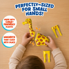 Top-down view of child assembling yellow giraffe magnetic toy on wooden table, snapping modular body parts together with hands visible. Callouts read perfectly sized for small hands, child-friendly plastic, and magnets that click into place for easy safe construction play.