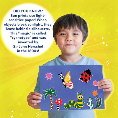 Young boy proudly displaying colorful cyanotype art with Sun Paper Art Kit in nature