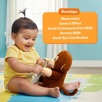 A happy toddler in a yellow polka-dot outfit sits on a colorful foam mat, lifting the soft cloth from a brown plush monkey’s face. An orange rounded box above lists developmental benefits in white text: “Observation, Cause & Effect, Social & Communication Skills, Sensory Skills, Hand-Eye Coordination.” The room background includes curtains and a light blue wall.