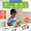 A young child happily plays with Brain Blocks at a table, stacking colorful geometric pieces and spheres into balanced structures. Above the child, icons and text highlight skill development areas including observation, critical thinking, problem solving, spatial reasoning, and fine motor skills. The scene emphasizes hands-on learning in a bright, child-friendly environment.
