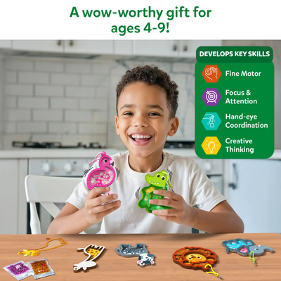 A smiling child sits at a table holding two animal-shaped confetti keychains, a flamingo and a crocodile. Additional foam animal pieces and confetti packets are spread on the table. A green panel highlights skill icons labeled fine motor, focus and attention, hand-eye coordination, and creative thinking. Text above reads “A wow-worthy gift for ages 4–9!”