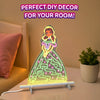 Skillmatics Light-Up Sketcher glowing on a bedside table as colorful artwork of a princess illuminates the transparent board. The setup includes a white stand and power cable, with a pink pillow, warm bedside lighting, and a potted plant in the background, illustrating room decor use.