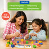 Adult woman and young girl sit at a wooden table smiling while building colorful 3D geometric structures using patterned blocks and spheres. Text above reads “TEACHES” with bullet points for shape recognition, pattern matching, sequencing, and early geometry. Challenge cards lie on the table, reinforcing hands-on learning and guided parent-child play.