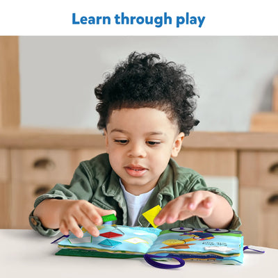 Young child playing with My Quiet Book sensory fabric activity book with colorful shapes
