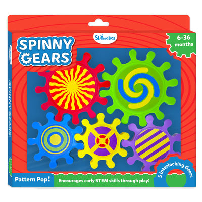 Skillmatics Spinny Gears Pattern Pop toy box shown at an angle on a red background. Five interlocking gears displayed: red sunburst, green blue-yellow spiral, blue concentric circles, yellow with purple cross, and purple with yellow stripes. Labels read ""6-36 months,"" ""5 Interlocking Gears,"" ""Pattern Pop!"" and ""Encourages early STEM skills through play!