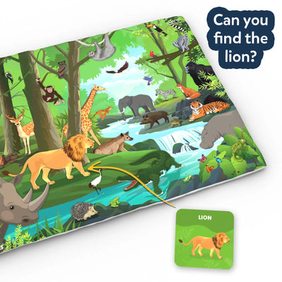 A jungle-themed cloth play mat is shown at an angle with a speech bubble reading “Can you find the lion?” The mat features a forest river scene with a lion, elephant, tiger, crocodile, giraffe, birds, and plants. A curved line points from a green lion card to the matching lion illustration on the mat.