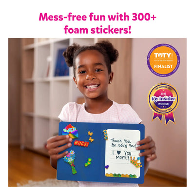 Child holding a blue magnetic board with colorful foam stickers and a note in Foil and Snip Creative Kit